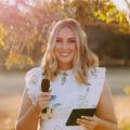Cassie Argus, a professional and warmly presented celebrant and MC, holding a microphone ready to host a joyful milestone celebration.